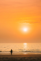 Fototapeta premium Silhouette Of Young Caucasian Lady Woman In Swimsuit Walking In Sea Beach During Sunset. Vacation On Ocean Beach. Sundown Above Sea Horizon At Sunset. Natural Sunrise Sky Warm Colors Over Ocean