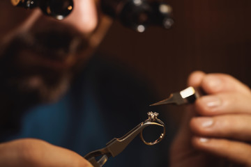 Jeweler working with ring on blurred background, closeup
