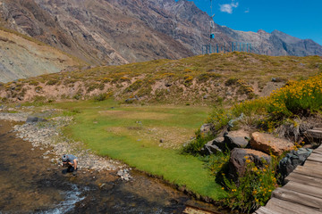 Fototapeta na wymiar rapaz tomando água no rio da cordilheira dos Andes no Chile