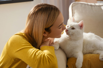 Young woman petting her beautiful white cat at home. Fluffy pet
