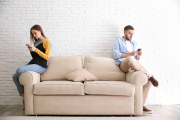 Couple addicted to smartphones ignoring each other at home. Relationship problems