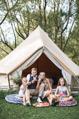Happy family wearing cowboy boho clothes, father, mother and two daughters sitting on pillows on...