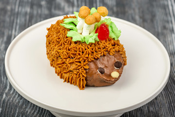 Dessert Russian cake in the form of hedgehog from sugar, butter, biscuits, cocoa, condensed milk with ornaments of butter cream