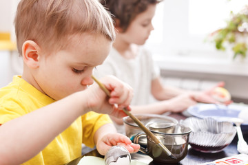 preparation for Easter. Glasses with colored paint and white eggs with a blue plate