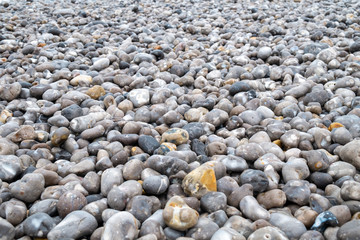 Close up of the pebbles on a beach in Normandy France, creating an Abstract smooth round pebbles sea texture background 