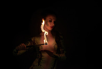 juggler girl performing fire games with python snake dress