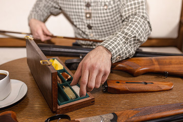 close-up photo of young caucasian man inspecting characteristics of rifle in guns store. man came to get the best weapon in salon