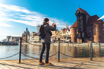 Theme of tourism in Poland. Traveling in Gdansk. A male traveler uses a phone on the embankment of...