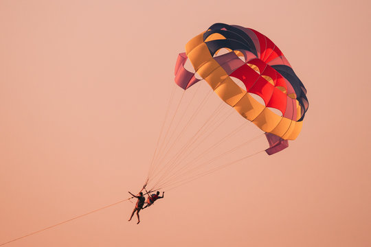 Parasailers Flying On Colorful Parachute In Sunset Or Sunrise Sky. Active Hobby