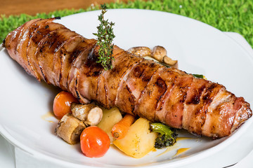 Bacon wrapped chicken fillet on plate with vegetables