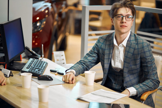 young successful handsome man in glasses sitting at workplace, close up photo. work, job, occupation, working hours. day, he is looking at the camera - Powered by Adobe
