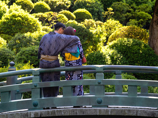 A young couple wearing kimonos cuddling on a bridge