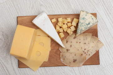 different types of cheese on a wooden board. Top view