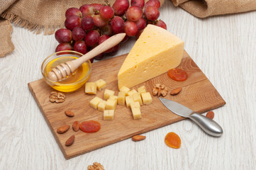 Cheese on a board with honey, nuts, dried apricots, grapes