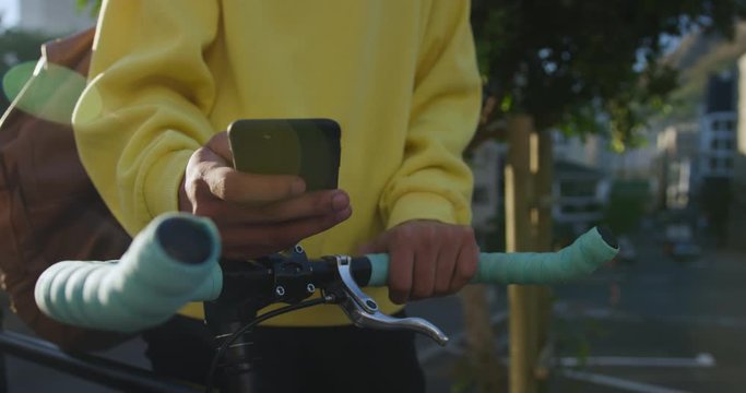 Transgender adult with a bike and using a phone