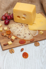 Fototapeta na wymiar Cheese on a wooden board with grapes, nuts, dried apricots