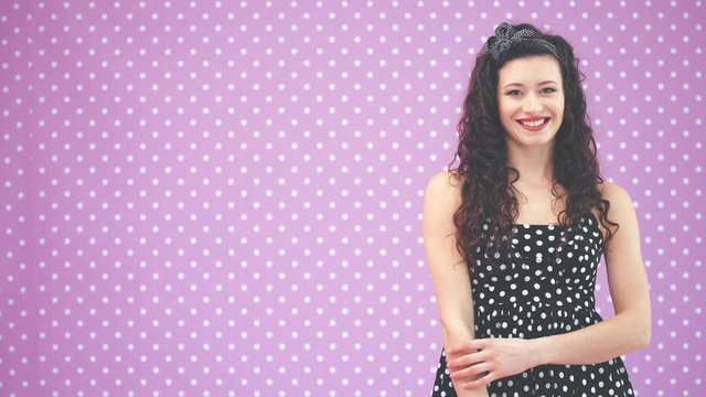 Beautiful young girl with kinky hair and black headband, wearing nice black polka-dots dress is looking at the camera, smiling.