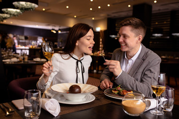 happy caucasian couple have dinner, dating in luxury restaurant. lady and guy enjoy spending time together. indoors