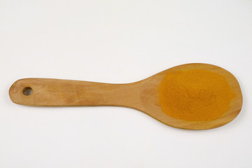 Turmeric powder in a wooden spoon isolated on a white background is an ingredient in turmeric foods and ingredients in skin care products. Turmeric helps the skin to be strong.