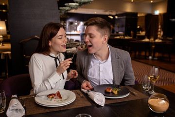 happy young caucasian couple spend their evening in restaurant. beautiful woman and man sit and enjoy meal together. romantic time of couple in restaurant