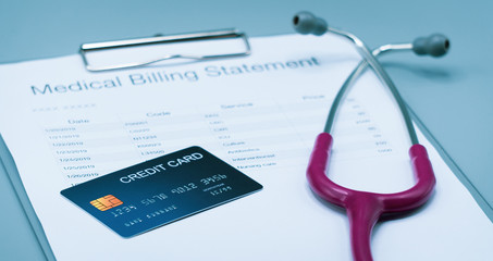 top view picture of medical billing statement, cradit card,  and pink stethoscope on the gray background