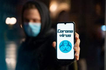 Man showing smartphone screen with coronavirus headline on it 