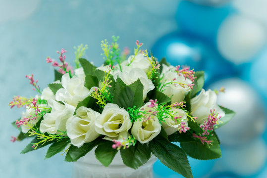 Beautiful bouquet of white roses with blurred background of blue balloons.