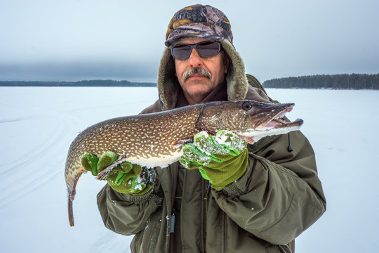 winter sport winter fishing, a man holding a large fish in his hands.