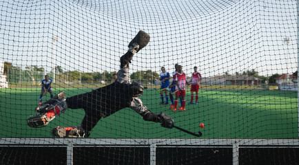 Rear view of hockey goalkeeper playing on pitch