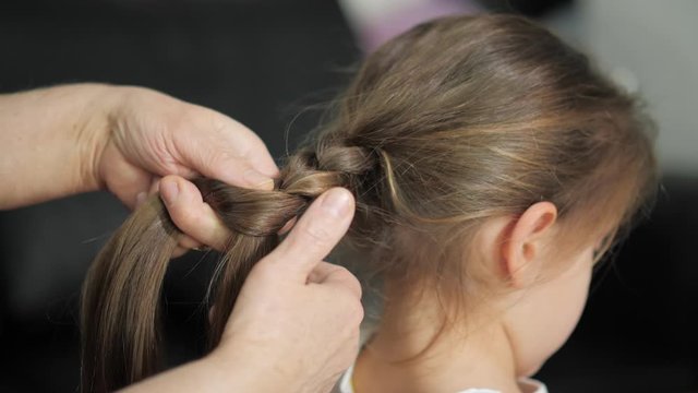 grandmother combs her granddaughter's hair, braid the ponytail