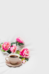Black coffee with pink roses on a white sheet