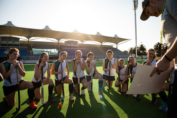 Female hockey players listening to the coach on the field