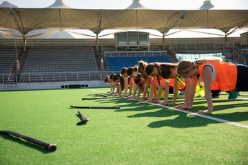 Female hockey players doing push-ups on the field