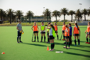 Female hockey players waiting on the field