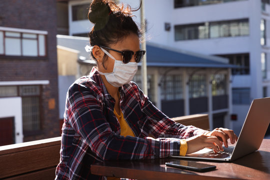 Woman wearing a Corona Virus face mask and using laptop