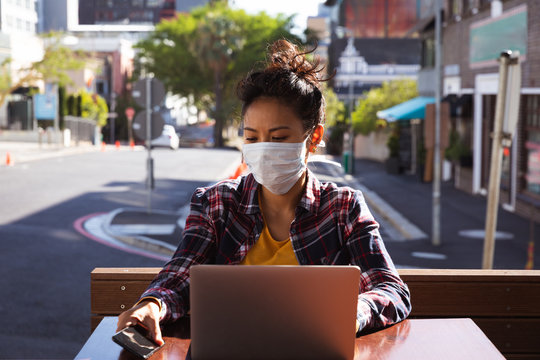 Woman wearing a Corona Virus face mask and using laptop