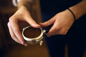 Fototapeta na wymiar coffee shop owner holding a portafilter containing freshly ground coffee, close up side view photo, blurred background.necessary component that is part of every espresso machine