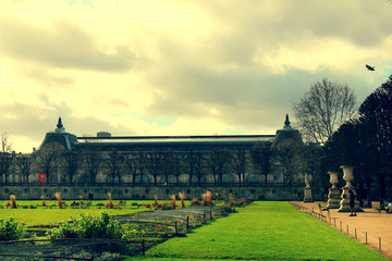  view of the famous Tuileries Park with a green lawn and an old building in the distance