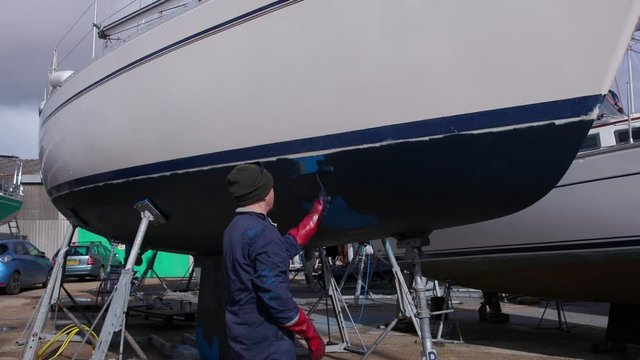 Sailing boat yacht being painted with antifoul paint