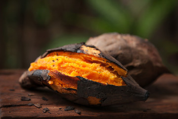 Grilled orange sweet potato put on wooden table with green nature background, Famous food in Autumn season at Japan