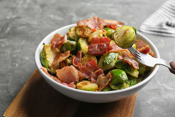 Delicious roasted Brussels sprouts with bacon served on grey table, closeup