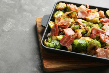 Delicious Brussels sprouts with bacon served on grey table, closeup