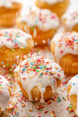 Sprinkling cupcakes with colorful  candy sugar sprinkles, close up. Gourmet dessert