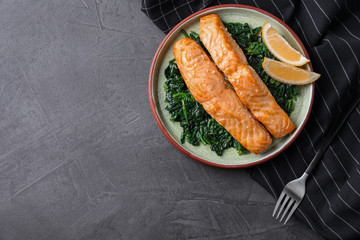 Tasty salmon with spinach and lemon on grey table, flat lay. Space for text