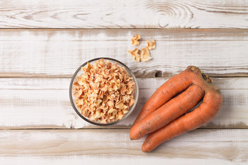 Non- standard ugly carrots and dried chips in a bowl on a wooden table. Rustic style. The image...