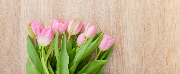 Rosarote Tulpen auf einem hellen Holztisch