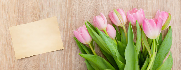 Rosarote Tulpen auf einem hellen Holztisch mit Postkarte