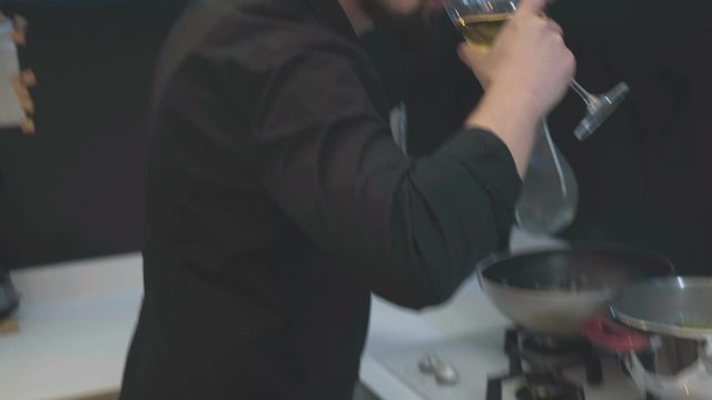 Young chef smiling and drinking wite wine.