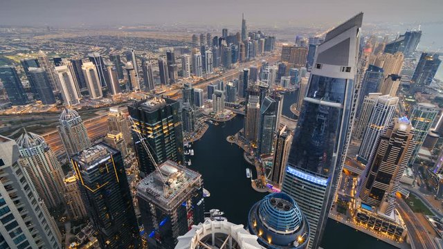 Dubai Skyline at dusk, aerial time lapse footage, with the Marina river and the city lights starting to glow 