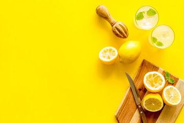 Fototapeta na wymiar Homemade lemonade in glasses near juicer and cut lemons on yellow background top-down copy space